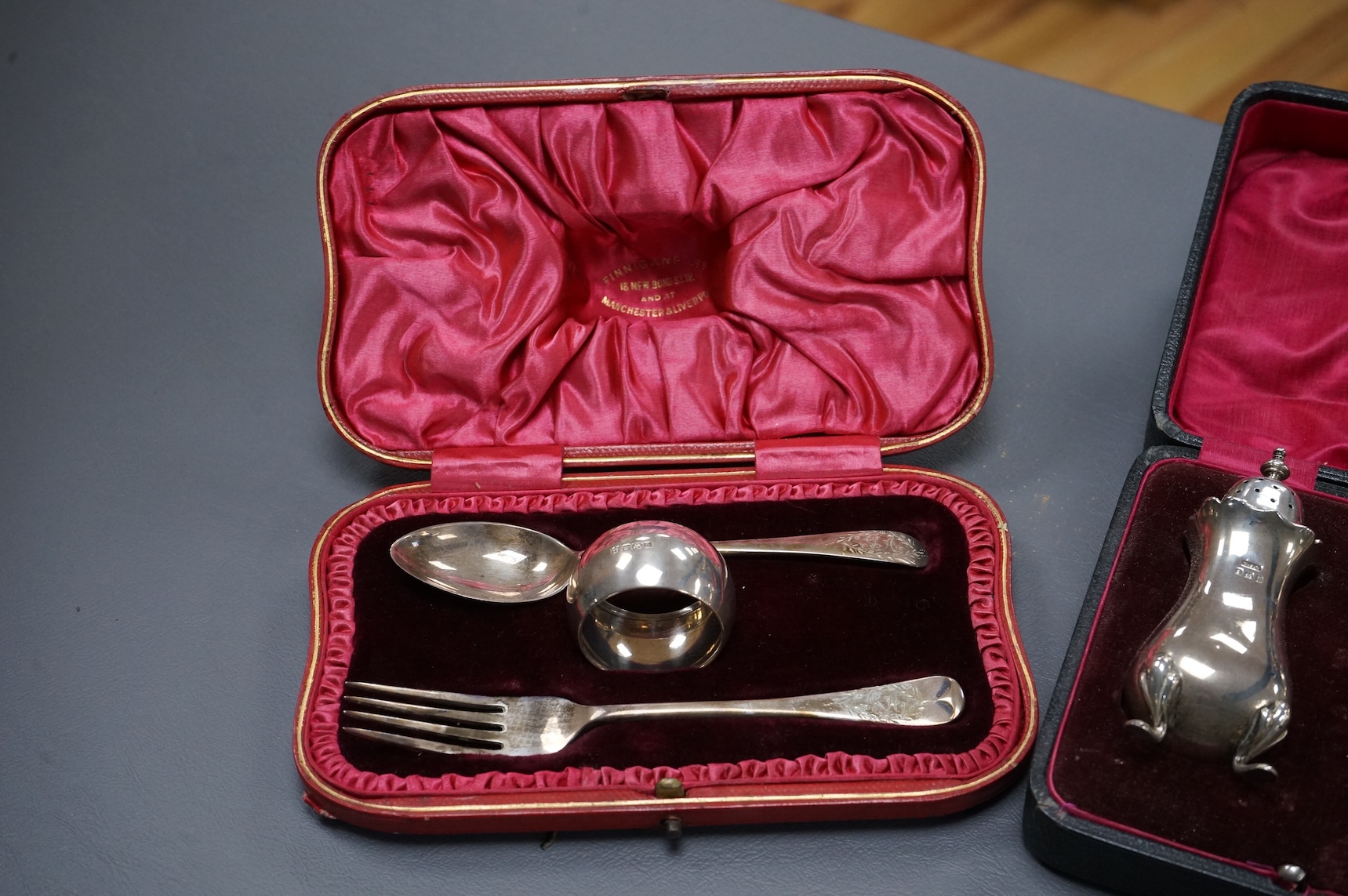 Three cased silver items including an Edwardian christening trio, a pair of George V pepperettes, Birmingham, 1916 and a George V pierced silver oval mustard pot, Birmingham, 1916.